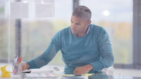 4K Designer working at his desk takes a break to turn &amp; look out of the window Stock Footage 76055700