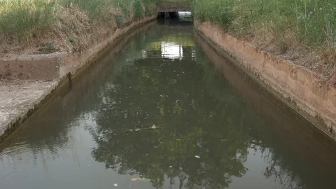 4K Ditch stream river water dirty acequia irrigation canal flowing bridge Stock Footage 113456622