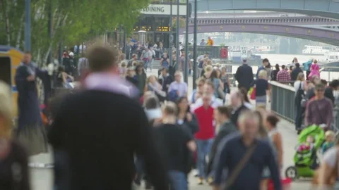 4K Diverse blurred crowd of people walk along the side of the River Thames Stock Footage