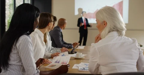 4K Diverse corporate group looking at graphs &amp; listening to speaker in a meeting Stock Footage 101357350