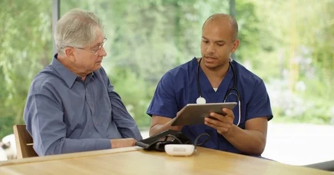 4K Doctor in appointment with elderly man, looking at test results on tablet  Stock Footage 83411460