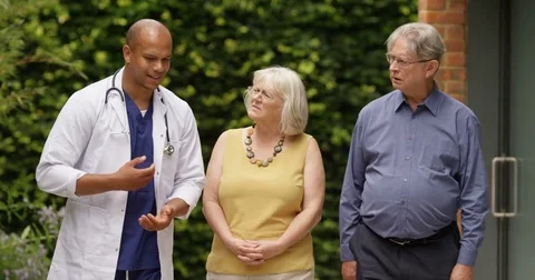 4K Doctor giving bad news to emotional senior couple outside hospital Stock Footage
