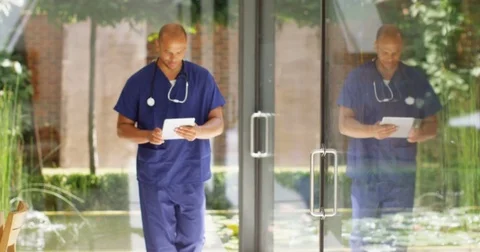 4K Doctor looking at digital tablet, walking through modern healthcare clinic Video stock 81174916