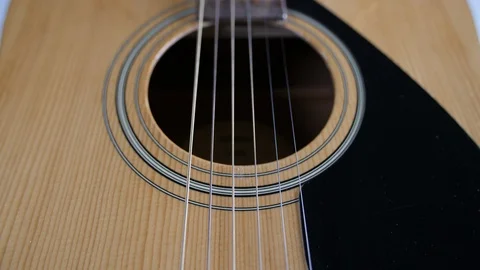 4k Dolly back over acoustic guitar, wooden strings along neck of instrument  Video stock 90148944