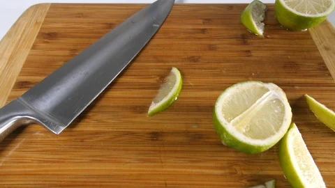 4k Dolly over top limes on kitchen chopping board slicing citrus fruit Stock Footage 90155119
