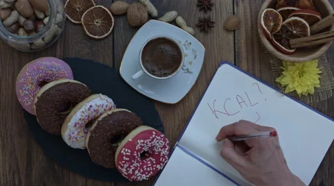 4k Donuts Composition on a Wooden Background with a hand writing Kcal? Vídeo Stock 65263956
