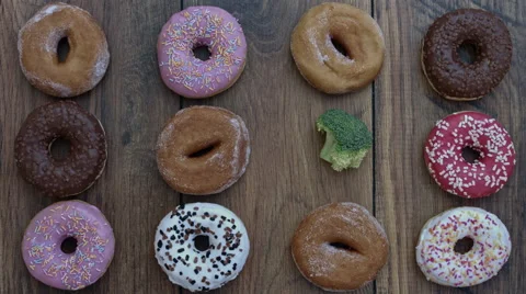 4k Donuts Composition on a Wooden Background with a Hand putting Broccoli Stock Footage 65264218