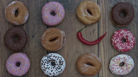 4k Donuts Composition on a Wooden Background with a Hand putting Chilli Video stock 65264950