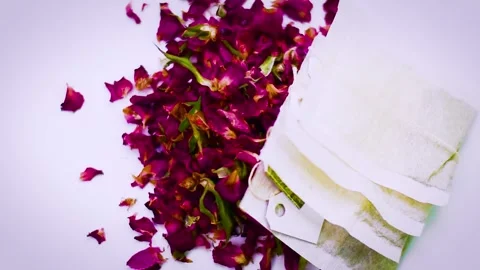 4K Dried Rose Petals Spilling with Tea Bags on White Background Stock Footage 336662750