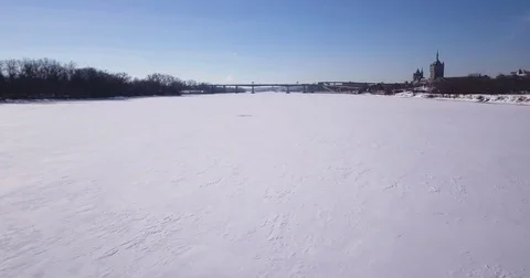 4k Drone aerial over a frozen lake towards a bridge during winter storm Stock Footage