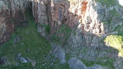 4K drone ascending from behind mountain revealing sea and distant coastal town i Video stock 329618096