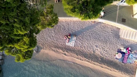 4K Drone Ascending Over Brela Beach with Couple Sitting and Tree Branches Stock Footage 312689291