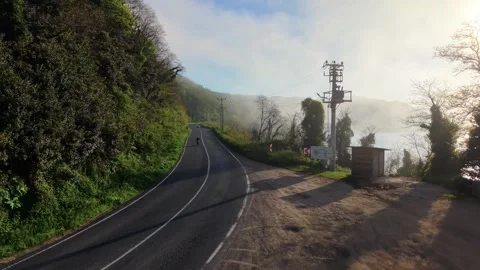 4K Drone Ascends Through Fog to Reveal Sunset Over Coastal Road 스톡 동영상 339275764