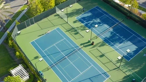 4K drone camera moves around a tennis court where there is an active game match 스톡 동영상 132747132