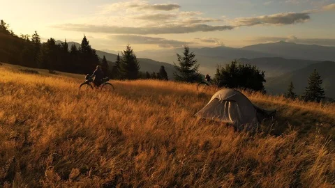 4k drone clip with two mountain bikes and a tent on a mountain meadow at sunrise 스톡 동영상 118082038