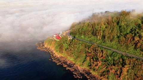 4K Drone Descending Toward Lighthouse Between Sea Fog and Sunset Stock Footage 339291969