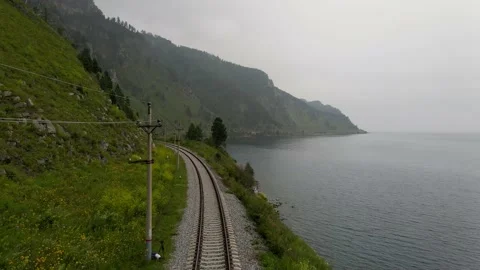 4K The drone flies forward and up over railway tracks between lake and the rocks Stock Footage 159394271