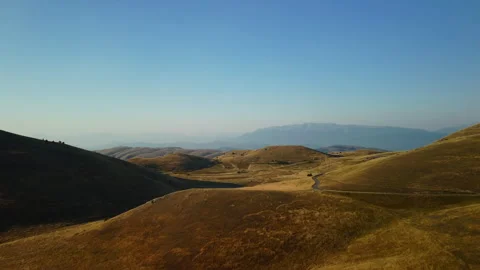 4K drone flight forward over yellow grassy hills with rocky mountains Stock Footage 315192831