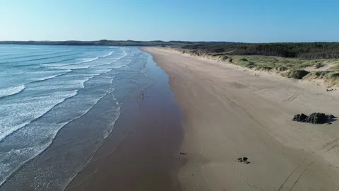 4K Drone Flight Over Sunny Beach in Wales with Sea and Pine Forest Видео 334030398