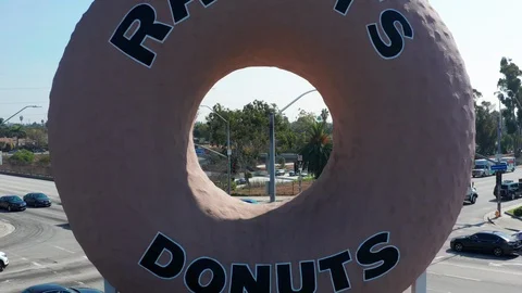 4K drone flying backwards through iconic Randy's Donut sign in Los Angeles Stock Footage 97560893