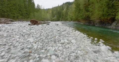 4k Drone Flying Forward Over Wide Rocky Riverbed In Canadian Evergreen Forest Stock Footage 264642689