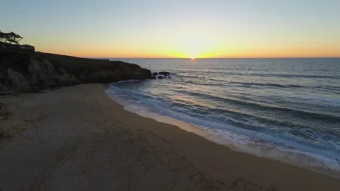 4k Drone flying over sand beach pacific ocean rocks torward sunset Stock Footage 73241691