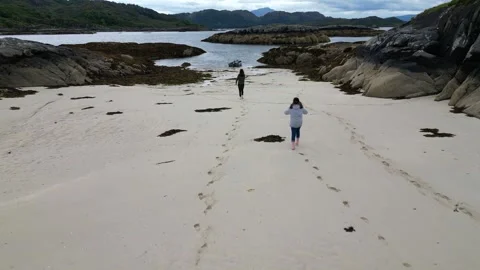 4k Drone flying over two people running on a Scottish beach towards the sea. Stock Footage 258342931