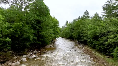 4K Drone Flying Slowly Downstream Swollen Small River in Vermont Stock Footage 246536352