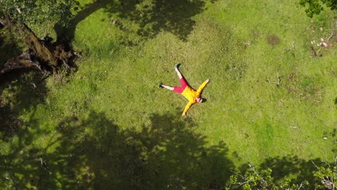 4K drone footage Man lying down on ground in star shape with arms flung to sides Stock-Footage 150986528