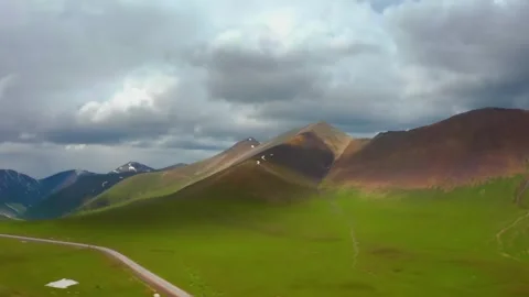4K Drone Footage of Mountain Range and Road Cutting Through Green Foothills in S Stock Footage 306604709