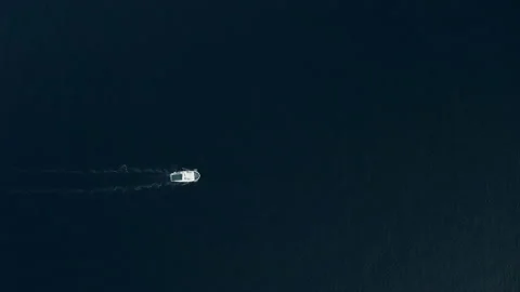 4K drone footage of tiny figure of white motor boat moving on ocean's surface Stock-Footage 143732812