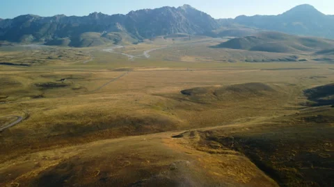 4K drone forward ascent over yellow hill with campers, valley and mountains Stock Footage 315197882