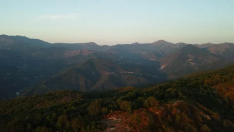 4K drone forward from orange forested mountains to mountain towns at sunset Stock Footage 315208396