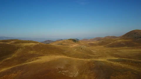 4K drone forward over barren yellow hills and mountain range in morning Stock Footage 315199250