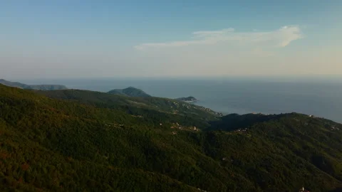 4K drone forward over forested mountains toward coastal city at sunset Stock Footage 315202405