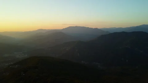4K drone forward over forested mountains with mountain towns at sunset Stock Footage 315203300