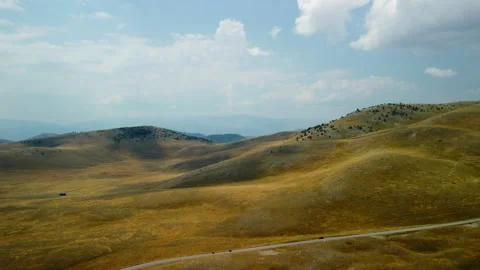 4K drone forward over yellow barren hills with road, cars and mountains Stock Footage 315198608