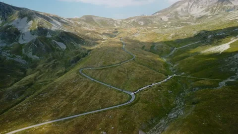 4K drone forward over yellow-green valley with road, cars, and mountains Stock Footage 315209868