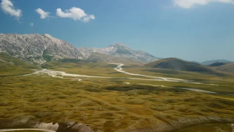 4K drone forward through mountain valley with green-yellow hills and mountains Stock Footage 315210794