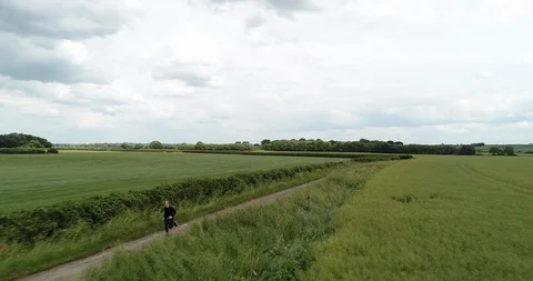 4K Drone of Man Running on a Path  through Green Grass Fields. British Summer Stock Footage 91233144