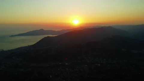 4K drone pan left to right over coastal city and forested mountains at sunset Stock Footage 315193973