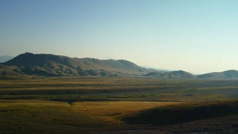 4K drone pan right to left over yellow-green valley with road and mountains Stock Footage 315194362