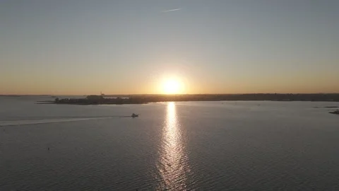 4k drone pushes toward a single boat crossing reflection of sunset Stock Footage 290946023