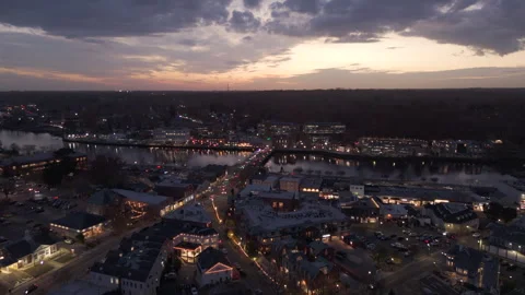 4k drone pushes toward sunset over small town split by river with bridge across Stock Footage 290993239