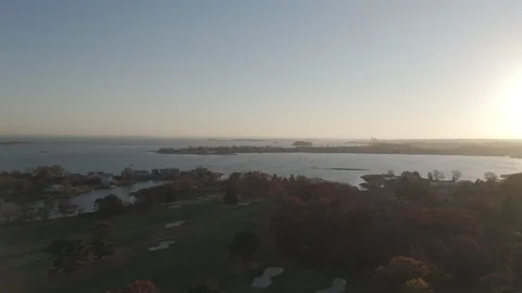 4k drone rotating left to right over golf course on the shore during sunset Stock Footage 290949250