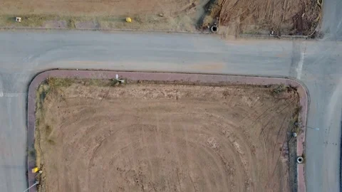 A 4K drone shot captures a 3-side corner residential plot on an empty street. Stock Footage 302154223