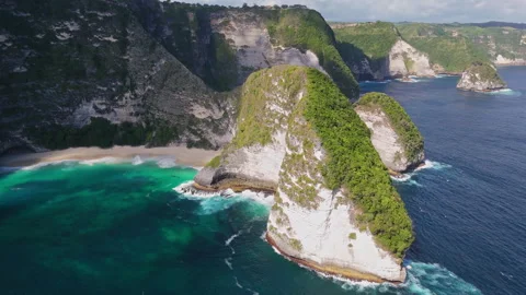 4K Drone shot of ocean wave washing over Kelingking Beach in Nusa Penida Video Stock Footage 276198423