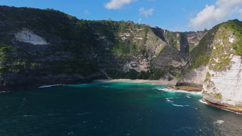 4K Drone shot of ocean wave washing over Kelingking Beach in Nusa Penida Video Stock Footage 276198531