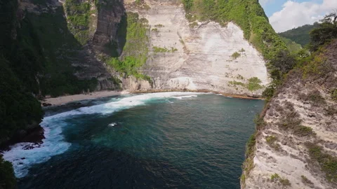 4K Drone shot of ocean wave washing over Kelingking Beach in Nusa Penida Video Stock Footage 276198701