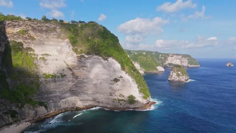 4K Drone shot of ocean wave washing over Kelingking Beach in Nusa Penida Video Stock Footage 276198981